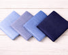 Four folded fabric swatches in blue and navy on a wooden surface