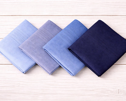 Four folded fabric swatches in blue and navy on a wooden surface
