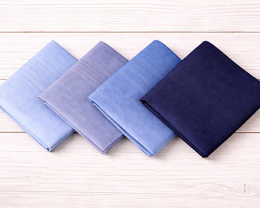 Four folded fabric swatches in blue and navy on a wooden surface