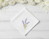 Pure white cotton handkerchief featuring centered violet lavender embroidery with green foliage on a light wood backdrop