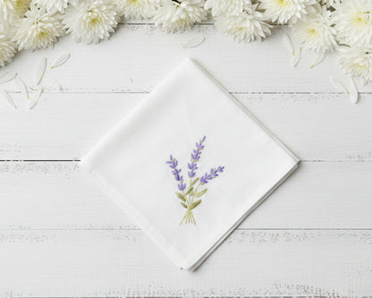 Pure white cotton handkerchief featuring centered violet lavender embroidery with green foliage on a light wood backdrop