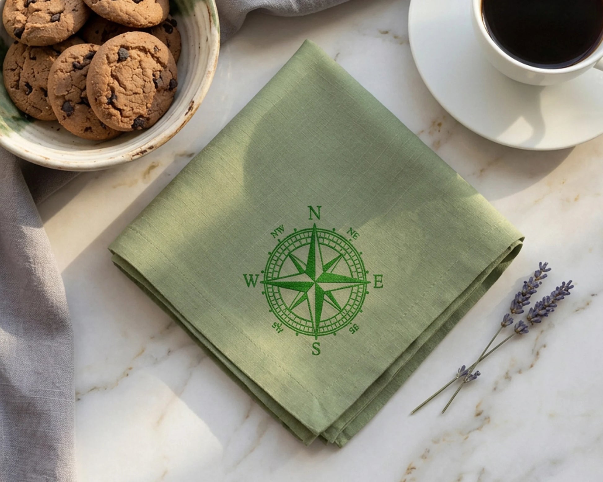 Green handkerchief with compass design on a marble surface with cookies and coffee.