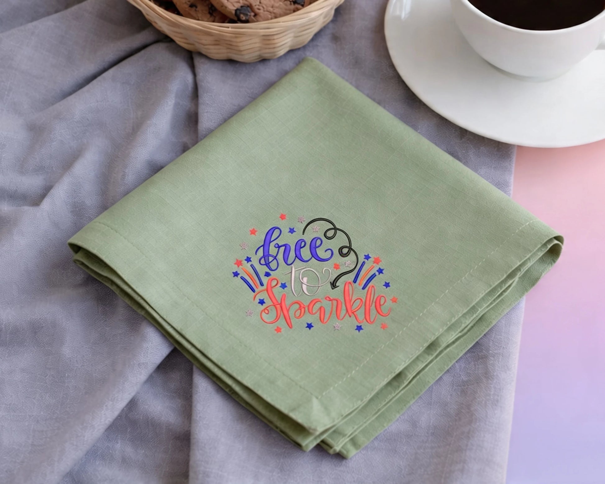 Green hanky with 'Free to Sparkle' text on a table with a cup of coffee and cookies.