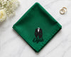 Green hanky with a tuxedo and 'Elijah' text on a white surface with flowers and rings.