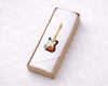 Guitar printed hanky in a cardboard box on a white surface