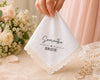 Handkerchief with 'Samantha BRIDE' text held by a hand, with flowers and jewelry in the background.