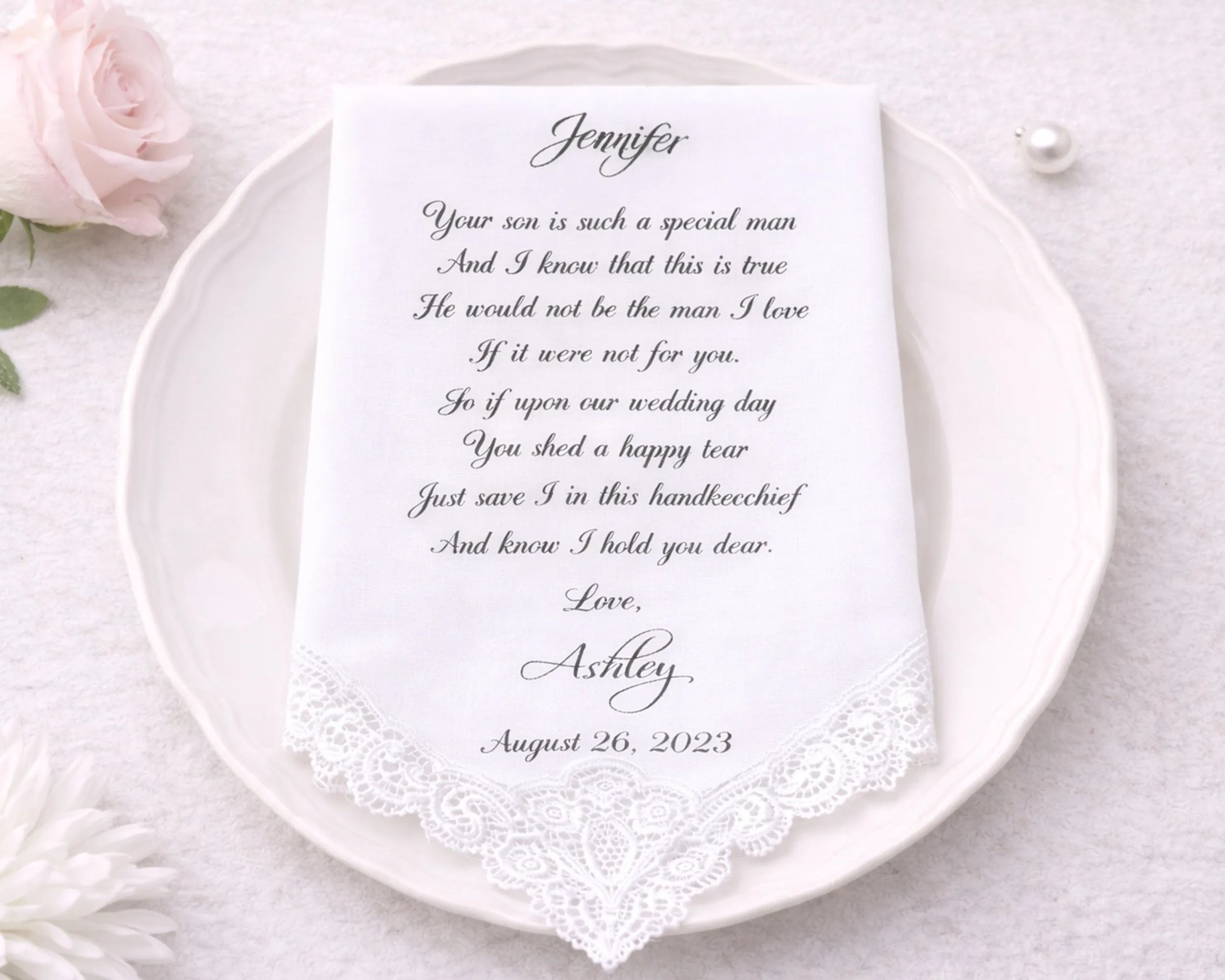 Handkerchief with a personalized message on a white plate, surrounded by flowers.