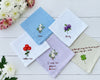 A variety of white, blue, and lavender cotton handkerchiefs with unique floral needlepoint designs and sentimental text