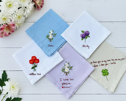 A variety of white, blue, and lavender cotton handkerchiefs with unique floral needlepoint designs and sentimental text