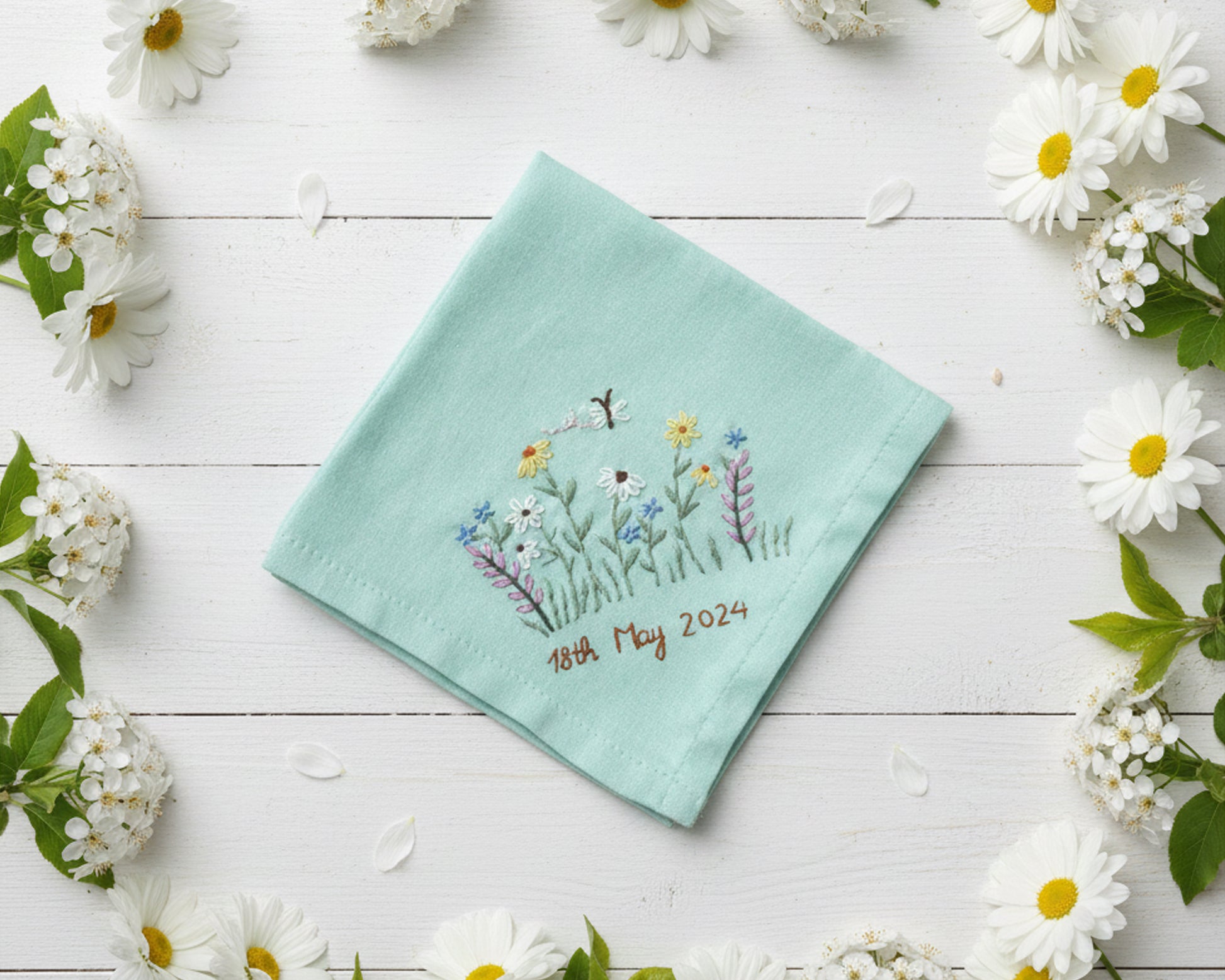 Mint green cotton handkerchief decorated with a colorful embroidered meadow scene and custom 2024 date