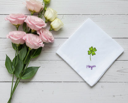 White cotton handkerchief decorated with a vibrant green four leaf clover and purple script name embroidery