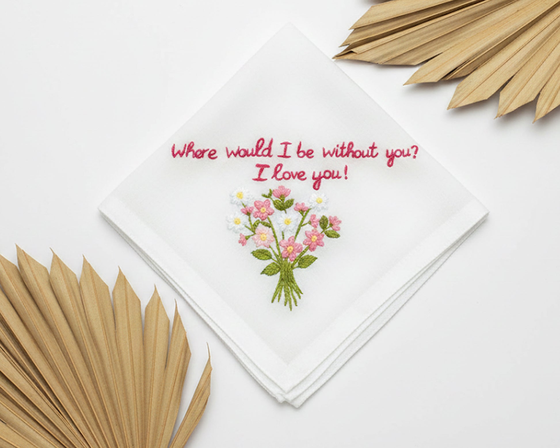 White cotton handkerchief decorated with a pink and white wildflower bouquet and sentimental red script embroidery