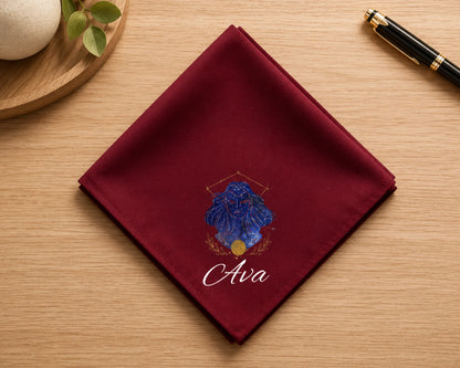 Maroon pocket square with blue floral design and 'Ava' text on a wooden surface.