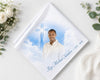 Memorial photo album with a cross and text on a white surface with flowers.