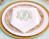 Monogrammed napkin on a gold-rimmed plate with a light blue background