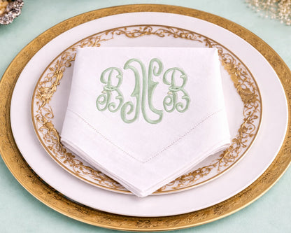 Monogrammed napkin on a gold-rimmed plate with a light blue background
