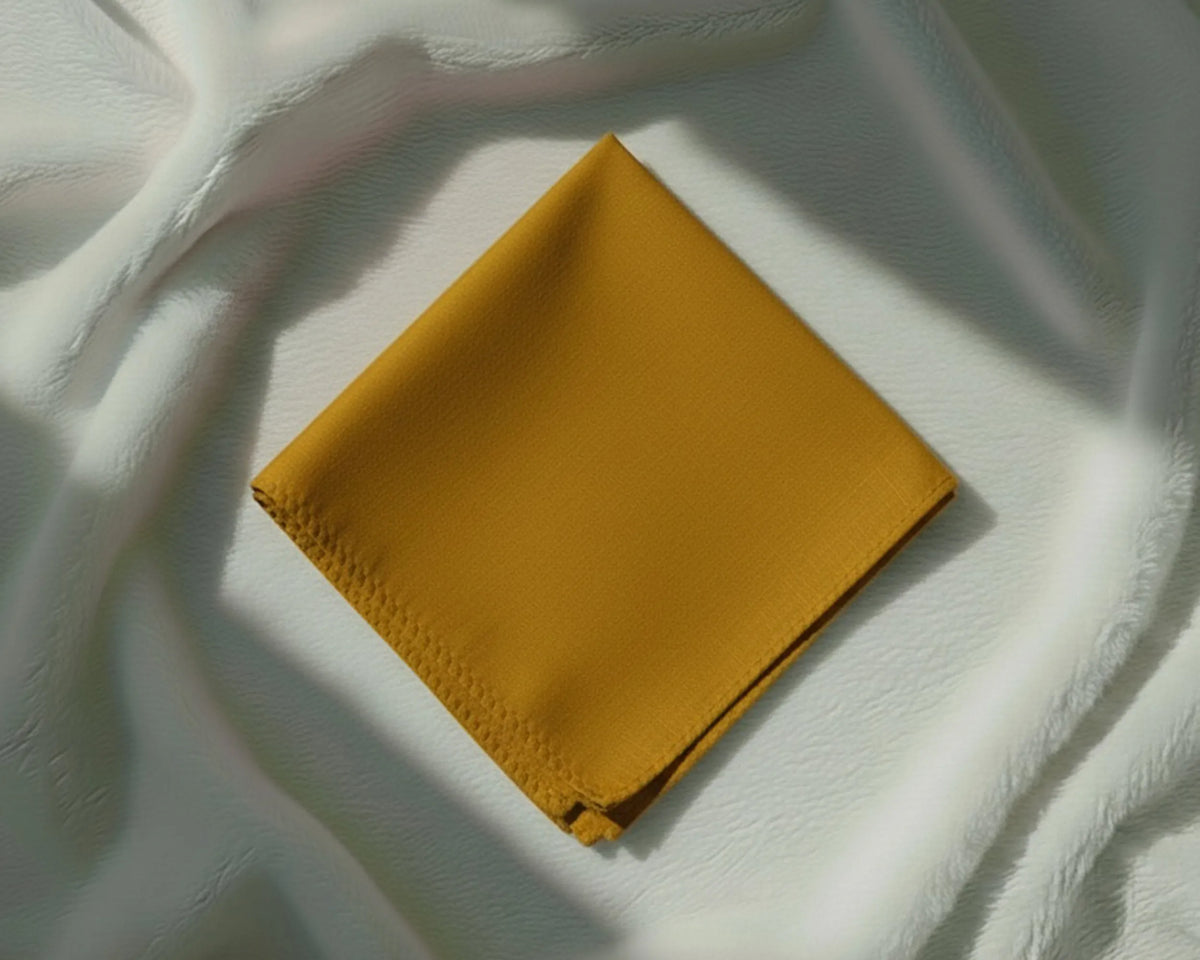 Mustard yellow fabric square on a textured white surface