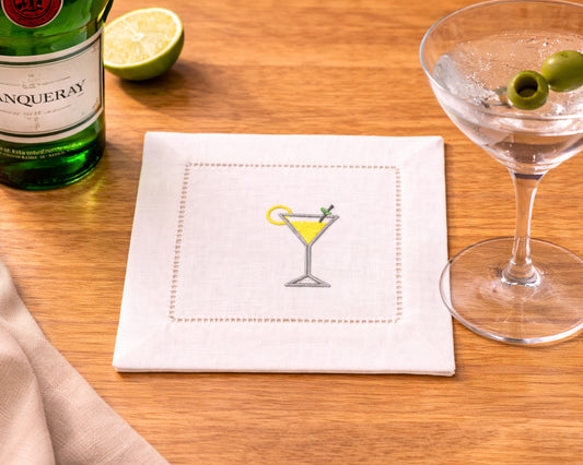 Napkin with cocktail illustration, bottle of Martini, and glass on wooden surface