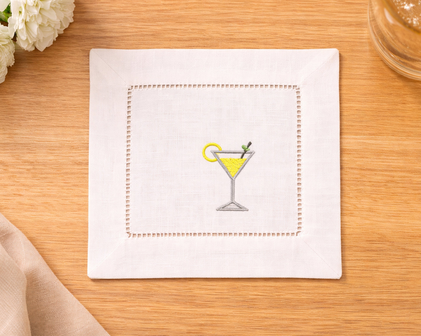 Napkin with embroidered martini glass design on a wooden surface