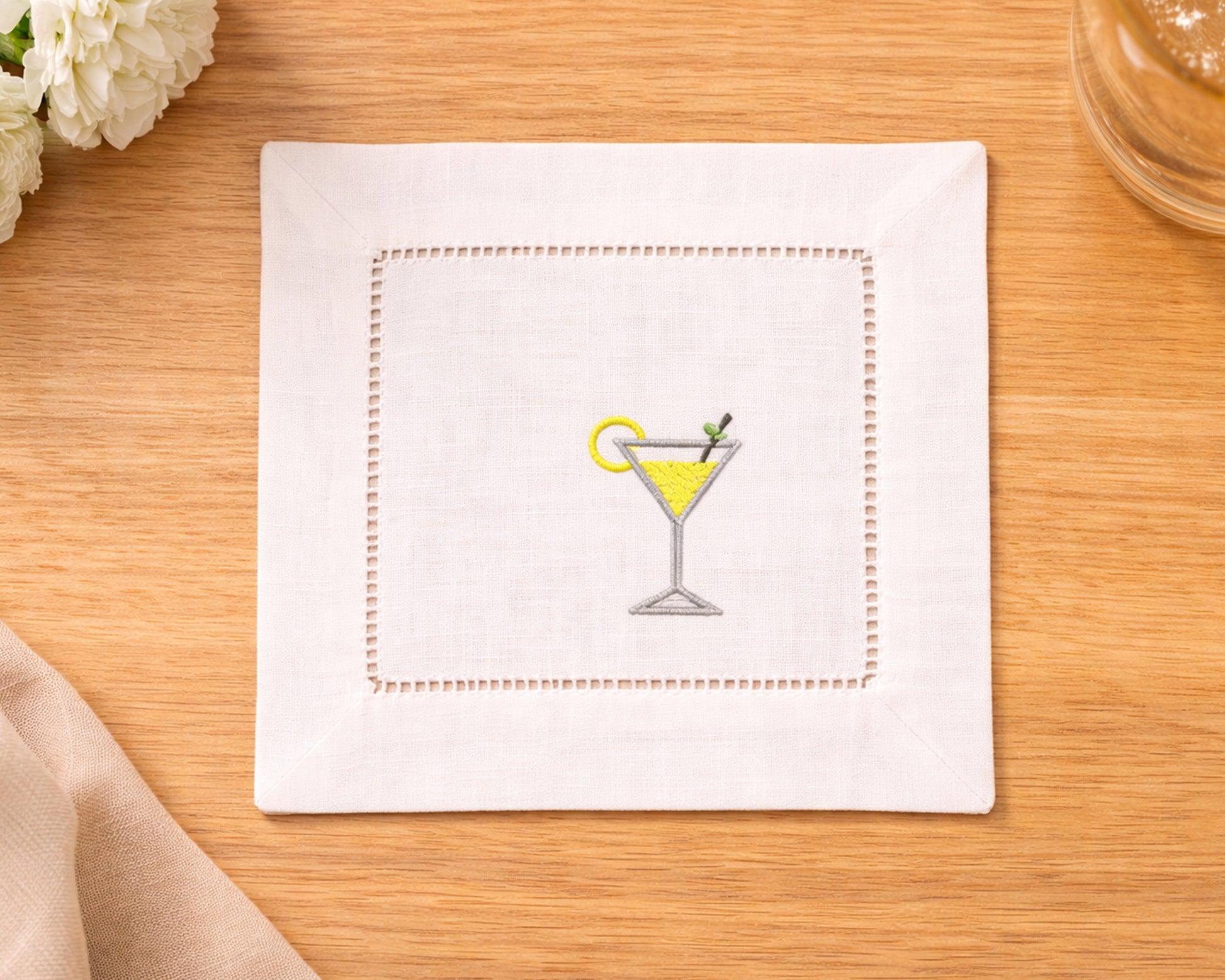 Napkin with embroidered martini glass design on a wooden surface