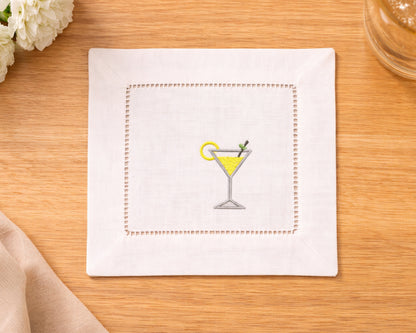 Napkin with embroidered martini glass design on a wooden surface