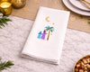 Napkin with palm tree and moon design on a table setting with candles and plates.