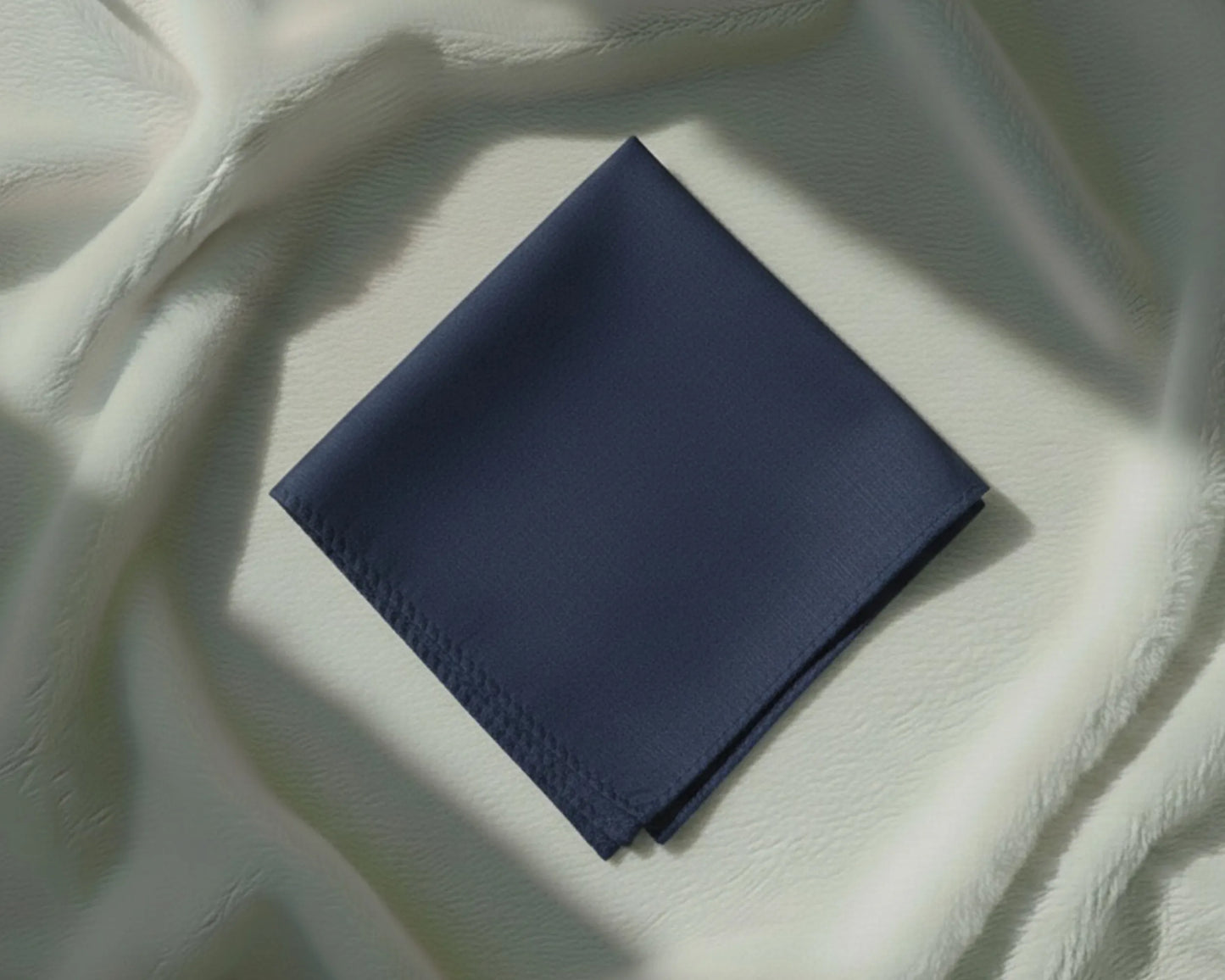Navy blue fabric square on a textured white surface