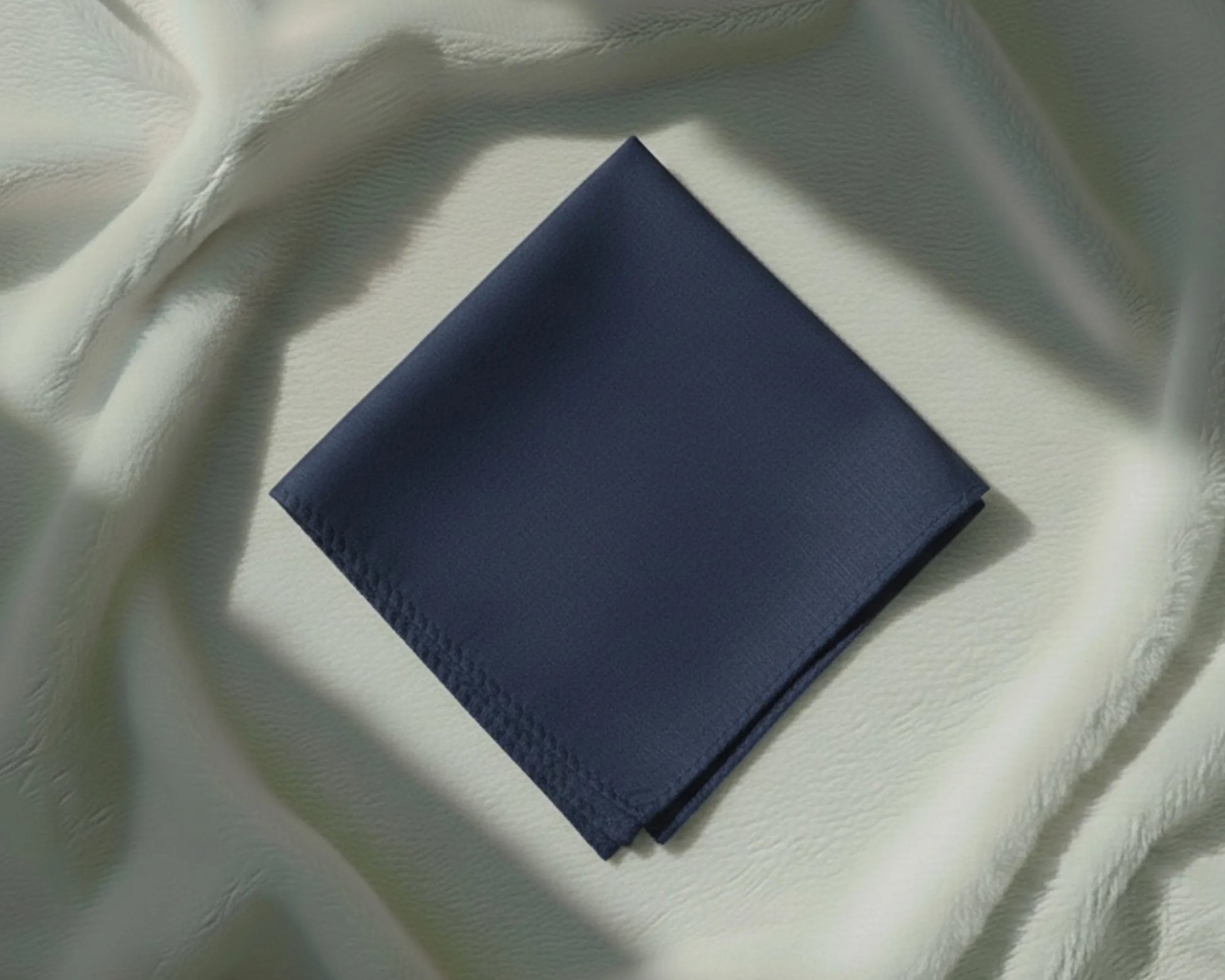 Navy blue fabric square on a textured white surface
