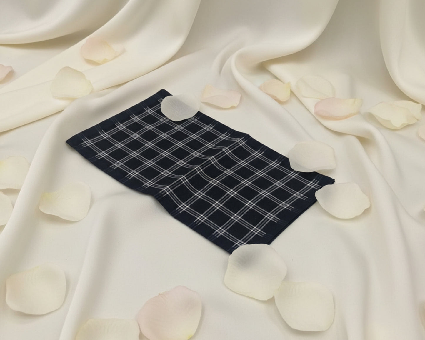 Navy blue checkered fabric on a white fabric background with scattered rose petals