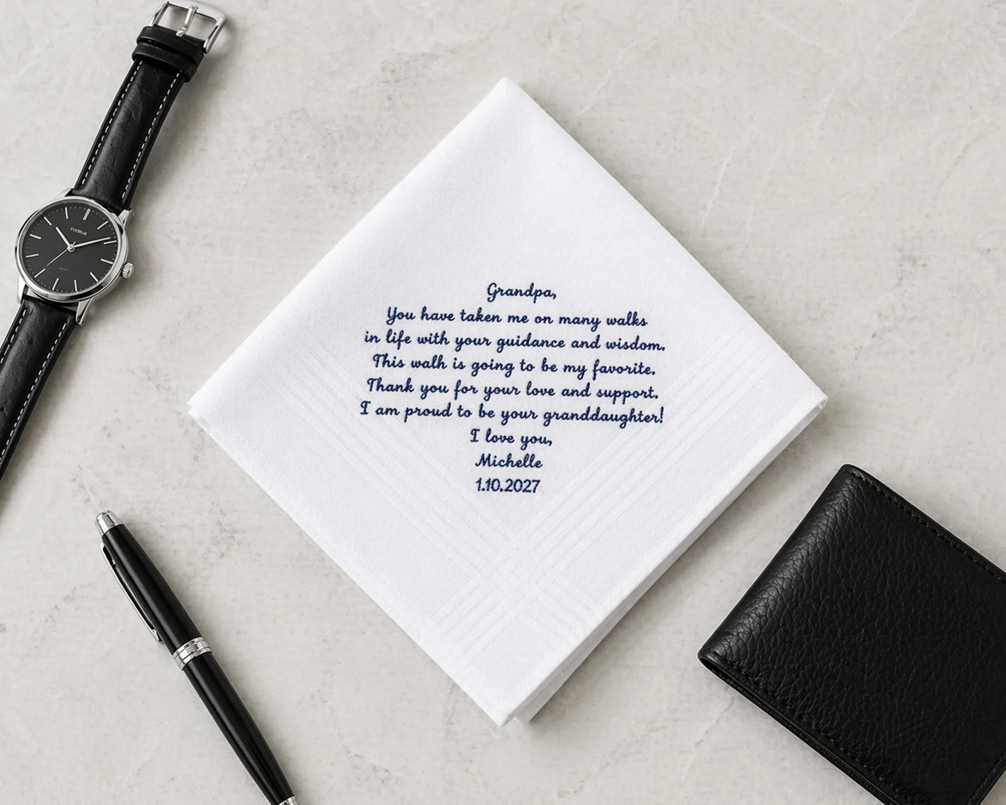 Notebook with a heartfelt message, pen, wallet, and watch on a light gray surface