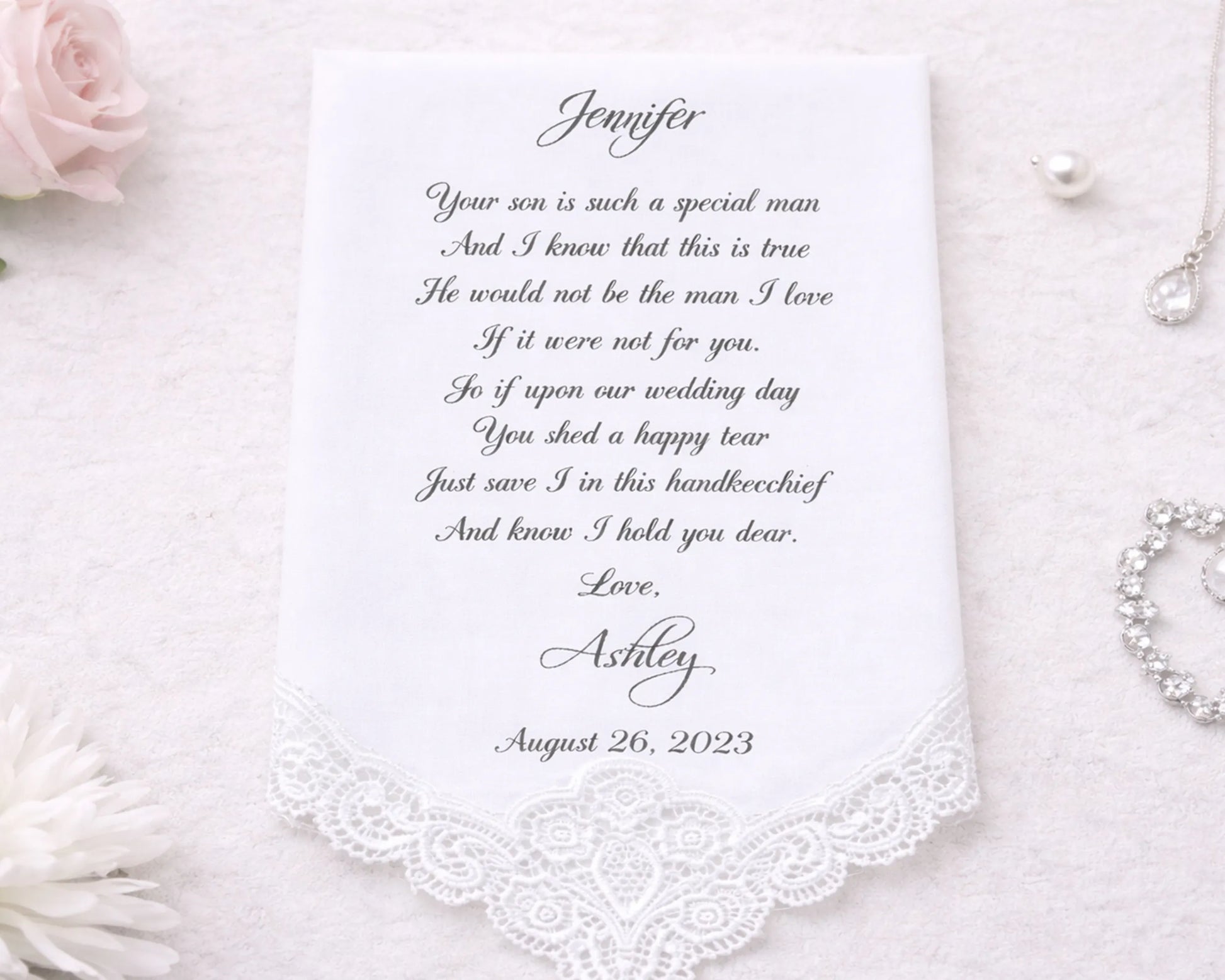 Personalized handkerchief with a heartfelt message on a white background with flowers and jewelry.