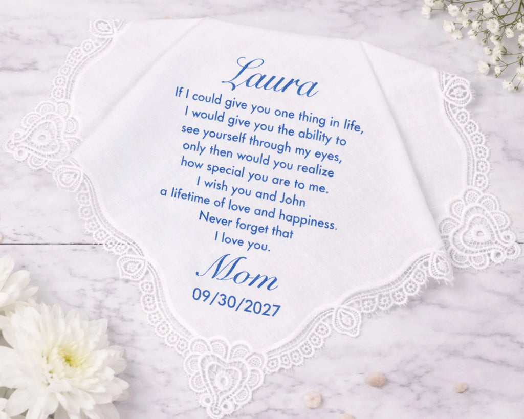 Personalized handkerchief with a message from 'Mom' to 'Laura' on a marble surface with flowers.