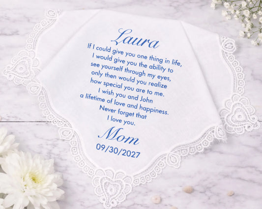 Personalized handkerchief with a message from 'Mom' to 'Laura' on a marble surface with flowers.