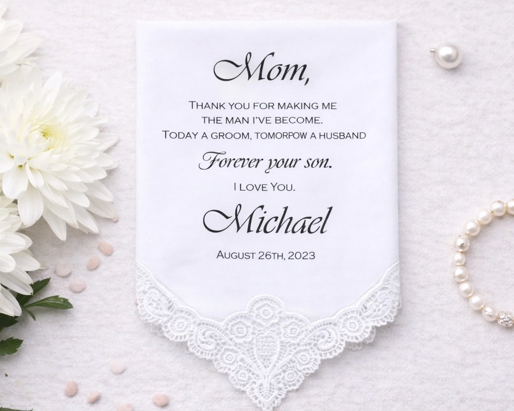 Personalized handkerchief with a message to 'Mom' on a white background with flowers and pearls.