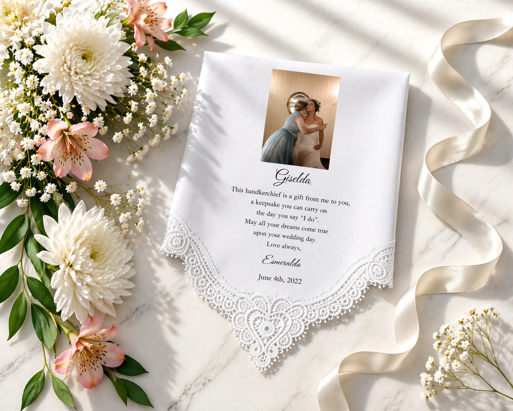 Personalized handkerchief with lace trim, photo, and text on a marble surface with flowers and ribbon.
