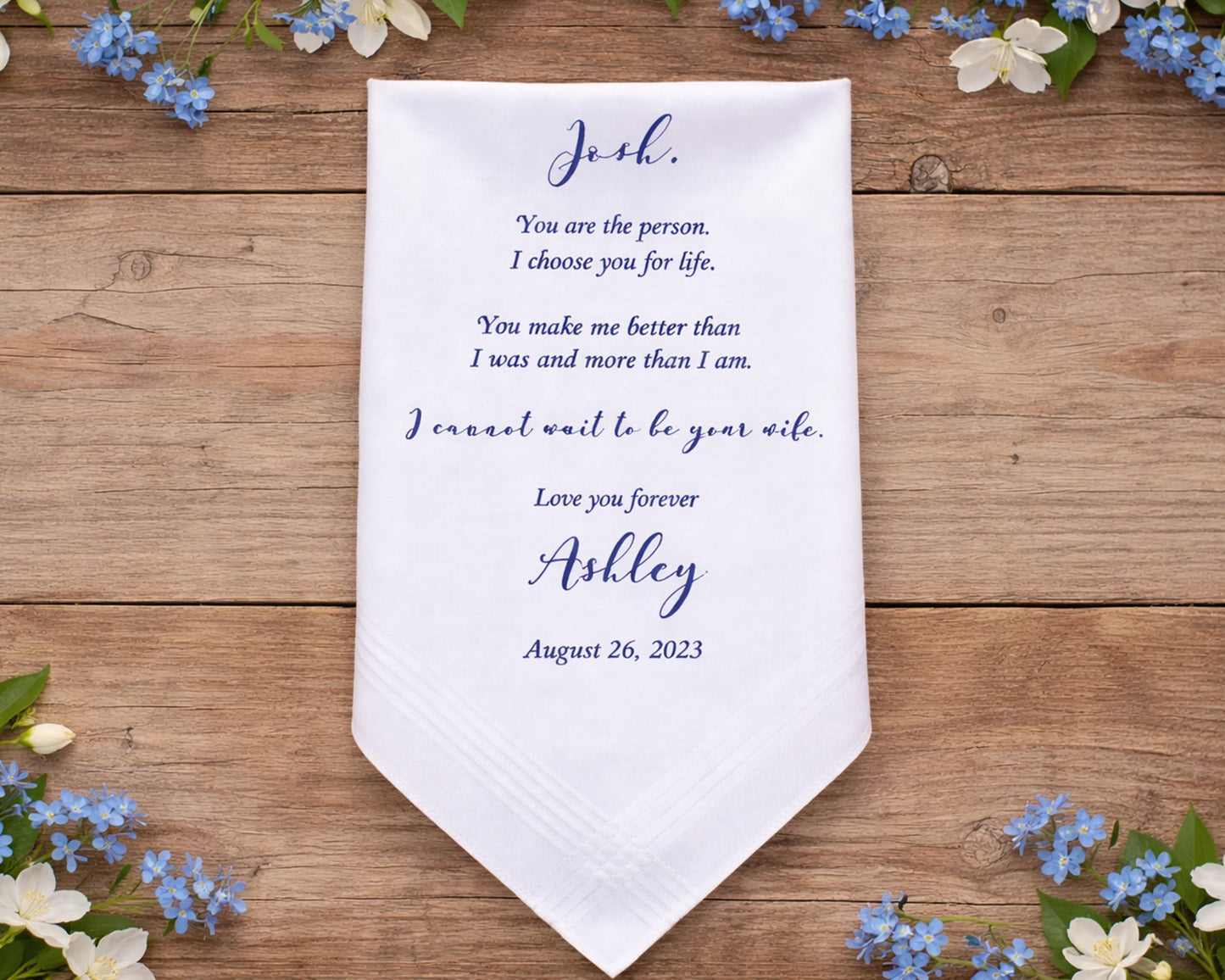 Personalized wedding handkerchief on a white wooden surface with flowers.