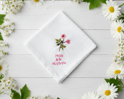 Personalized white cotton handkerchief with delicate pink floral needlework and custom red date embroidery framed by daisies