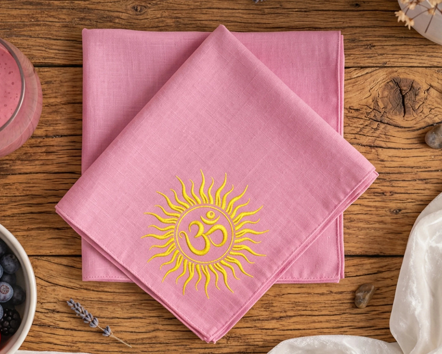Pink hanky with a yellow sun and Om symbol on a wooden table.