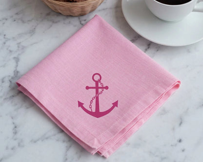 Pink hanky with an anchor design on a marble surface with a cup of coffee.