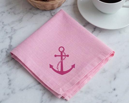 Pink hanky with an anchor design on a marble surface with a cup of coffee.