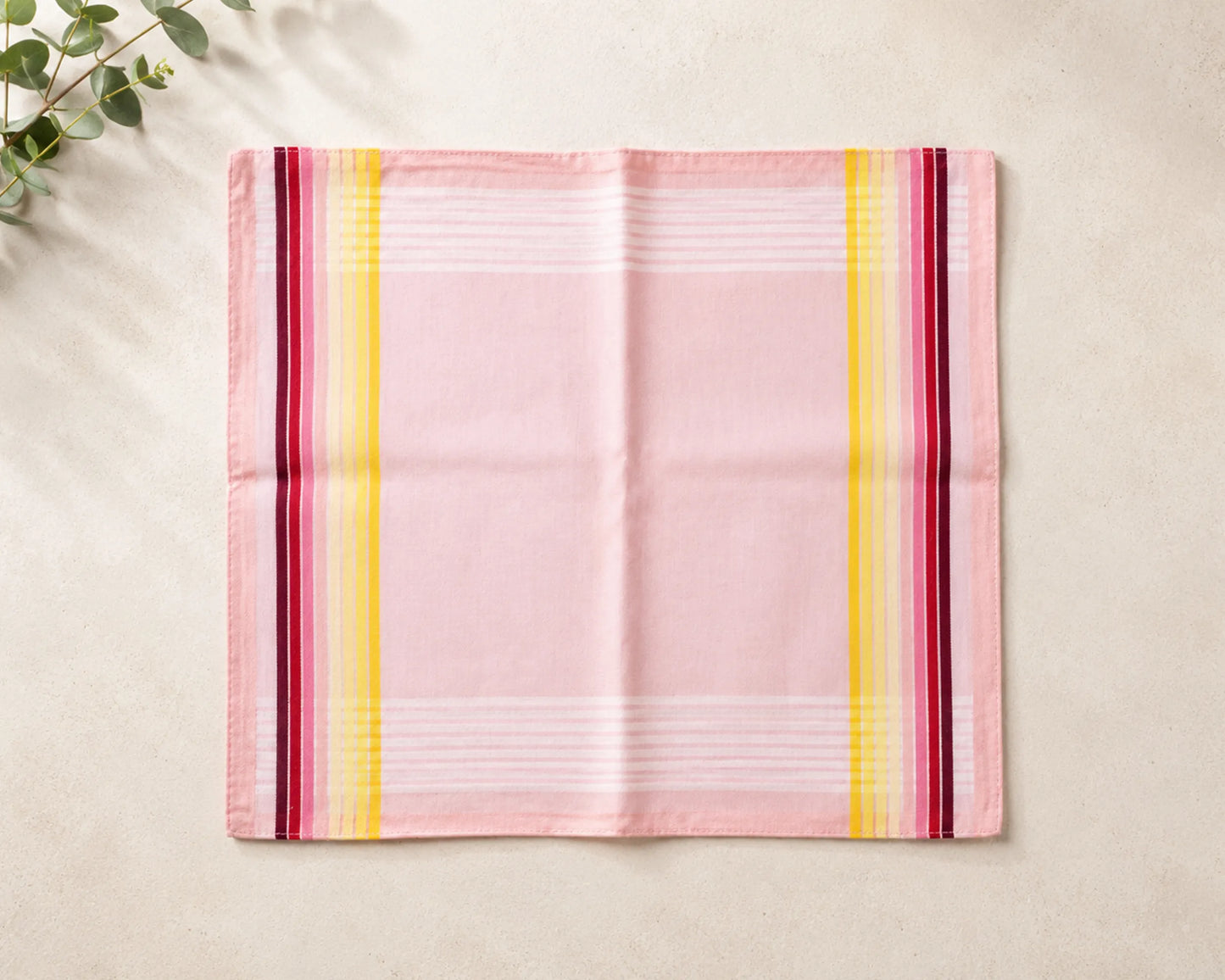 Pink hanky with colorful stripes on a beige surface