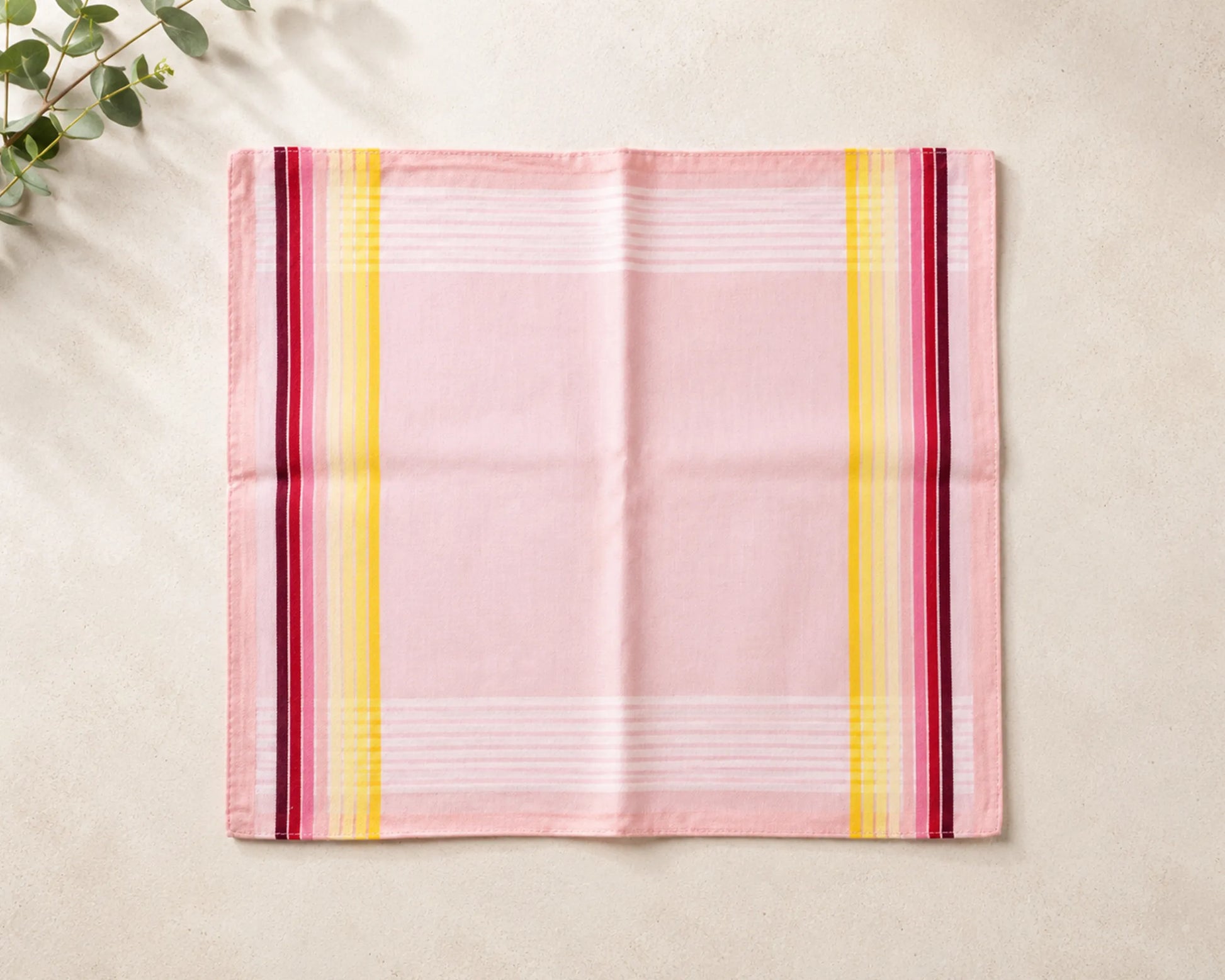 Pink hanky with colorful stripes on a beige surface