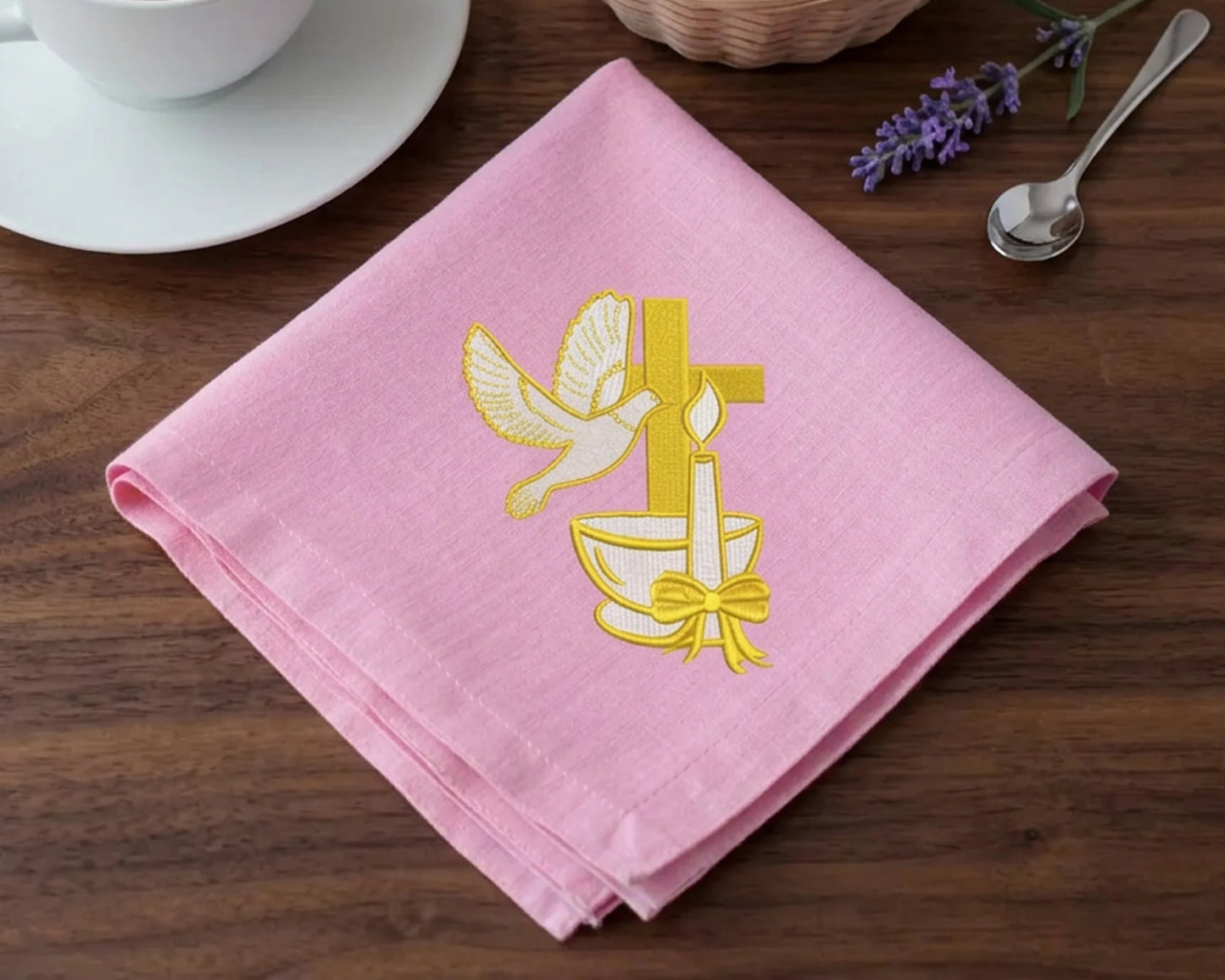 Pink hanky  with yellow cross and dove design on a wooden table.