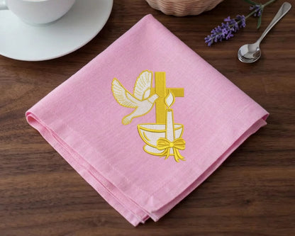 Pink hanky  with yellow cross and dove design on a wooden table.