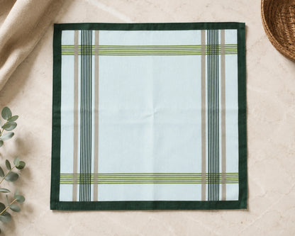 Plaid cotton hanky on a beige surface with a woven basket and green leaves.