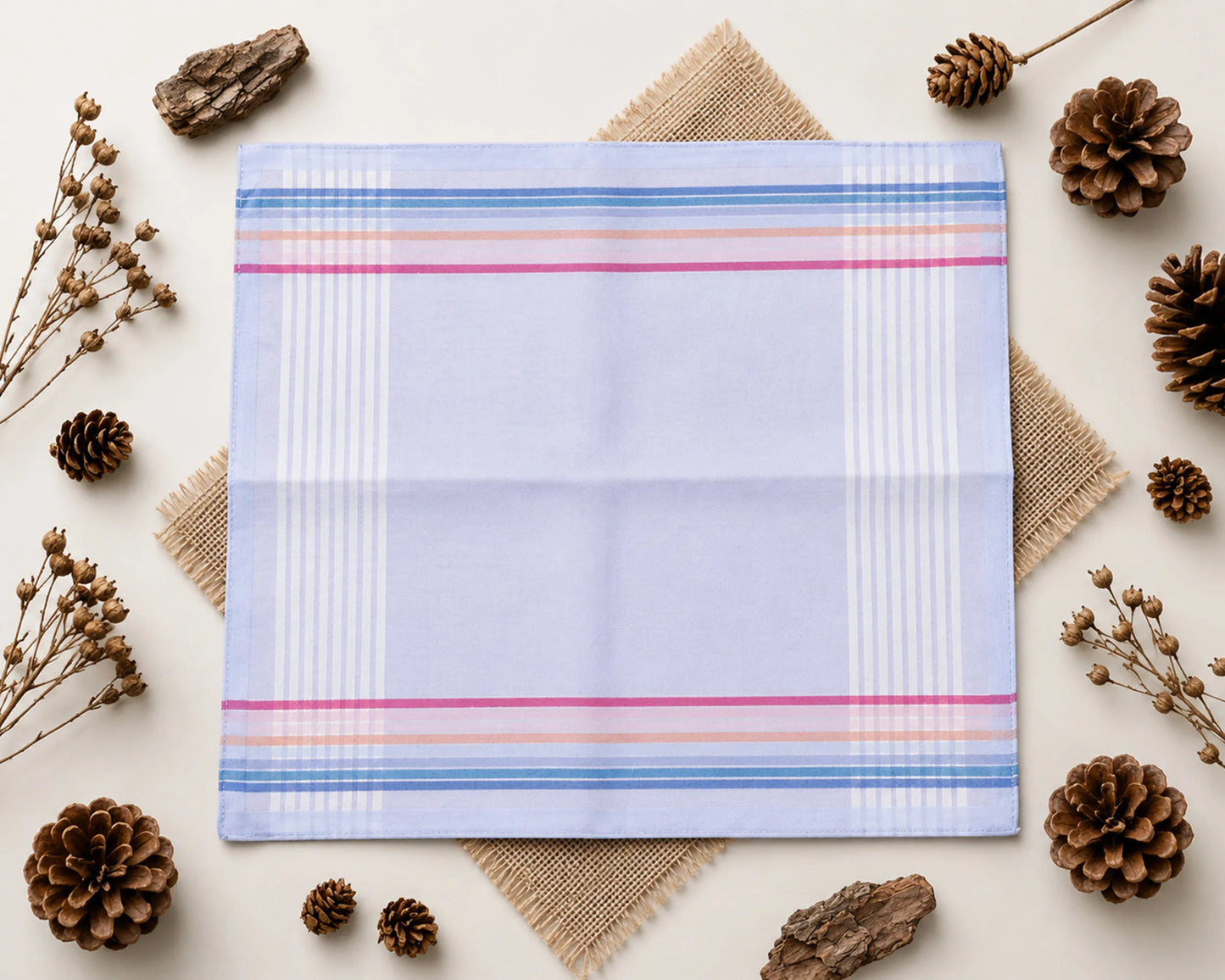 Plaid fabric with colorful stripes on a light background with decorative elements like pine cones and twigs.