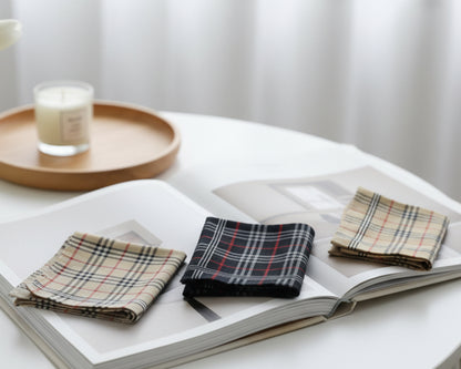 Plaid hanky on an open book with a candle on a wooden tray in the background.