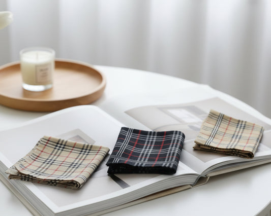 Plaid hanky on an open book with a candle on a wooden tray in the background.