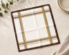 Plaid hanky with brown, yellow, and gray pattern on a light surface.