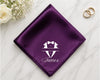 Purple pocket square with a tuxedo design and 'James' text on a marble surface with flowers and rings.